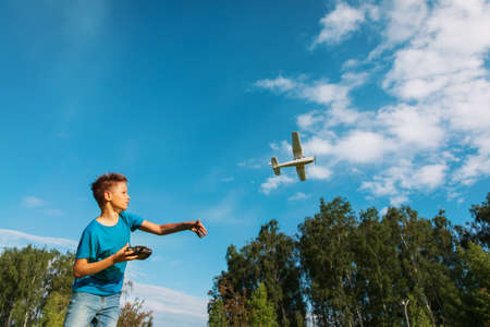 boy flying remote controlled plane in natureの写真素材