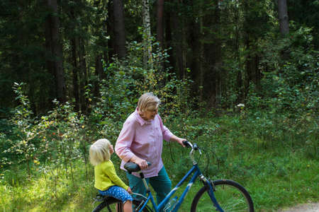 grandmother with little granddaughter on bike ride in natureの写真素材