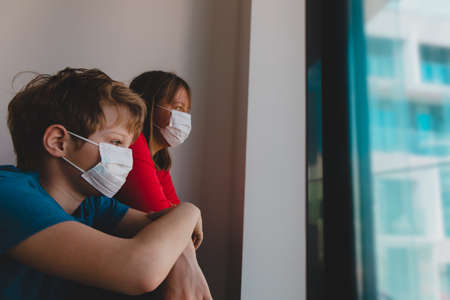mother and son with masks stay home, family looking at the windowの写真素材