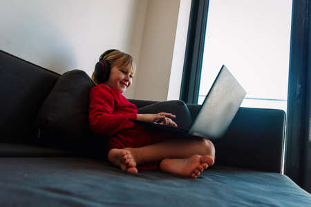 little girl learning remotely at home, kid with laptop indoorsの写真素材