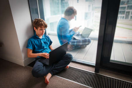 father working remotely on the balcony while son on distant learning at home