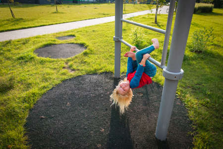 happy cute little girl upside down on monkey bars
