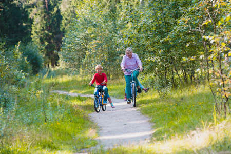 active senior grandmother with kids riding bikes in natureの写真素材
