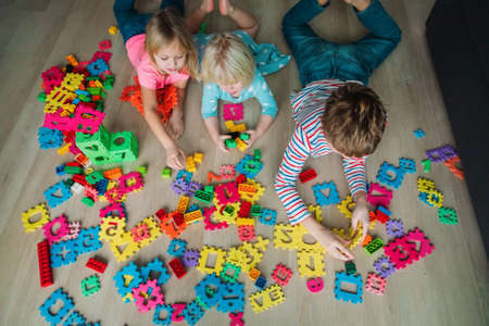 kids playing with pouzzle and plastic blocks, family staying home,の写真素材