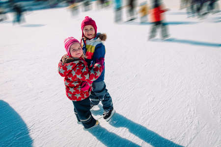 happy little girls hug while skating togetherの写真素材