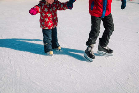big brother teaching little sister to skate in winter