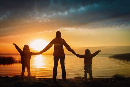 happy mother with kids looking at sunset on lakeの写真素材