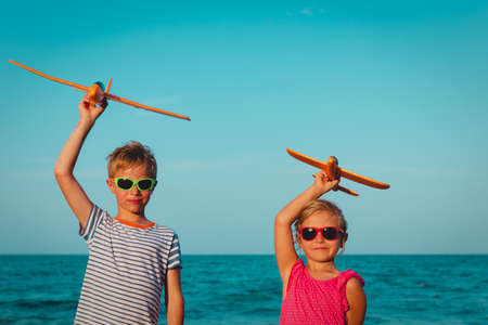 happy boy and girl flying toy planes on beach vacation