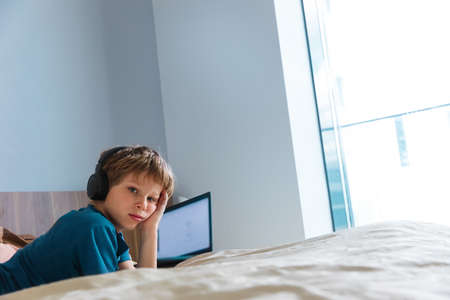 Bored and tired boy with a laptop, remote learning during quarantine.の写真素材