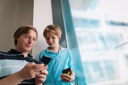 father and son looking at mobile phones while staying homeの写真素材