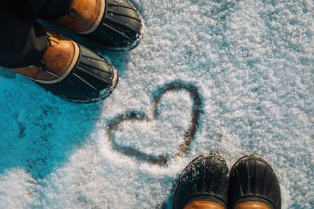 love winter - feet in snow boots and heart in natureの写真素材