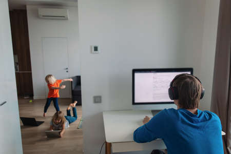 family stay home, father work on computer while kids dance and have funの写真素材