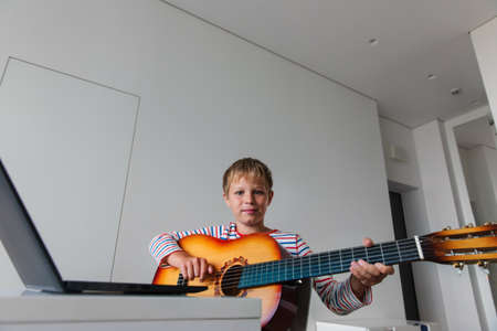 kid having guitar lesson online, teenage boy on remote music lesson