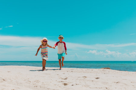 happy boy and girl running on tropical beachの写真素材