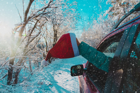 christmas travel, driving on car with with santa hat in snowの写真素材