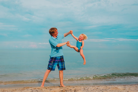 happy father and little daughter play at beachの写真素材
