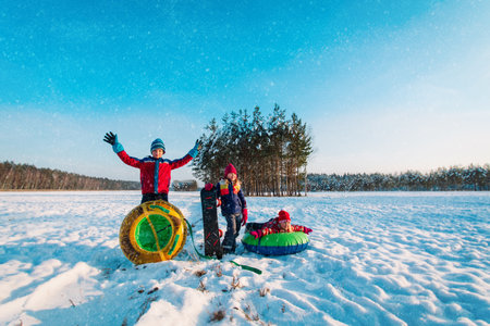 happy kids go to slide in winter snow, kids have fun outsideの写真素材