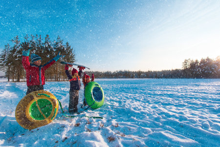 happy kids go to slide in winter snow, kids have fun outsideの写真素材
