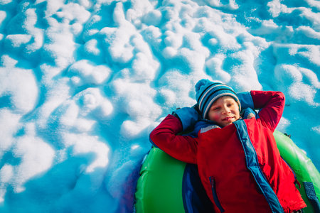 happy cute boy enjoy slide in winter snowの写真素材