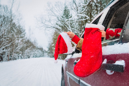 christmas family travel by car, family with santa hat and socking on road in snowの写真素材