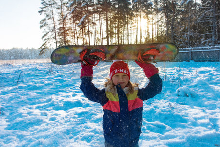 Snowboard winter sport. Cute girl with snowboard going to slide in winter natureの写真素材