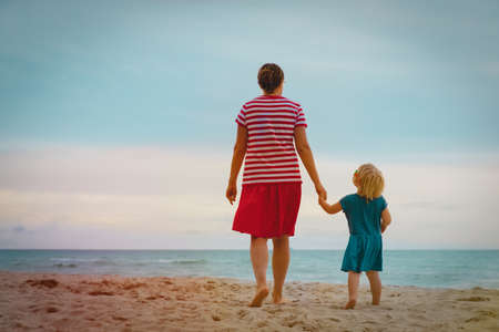 Back view of mother and daughter walking at beach enjoying tropical vacationの写真素材