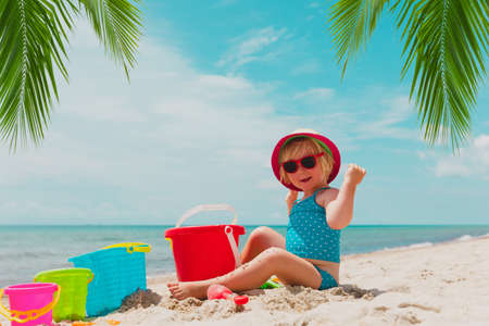 cute little girl playing with sand on tropical beachの写真素材