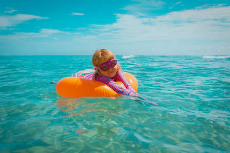 cute happy little girl swimming on floatie at tropical beachの写真素材