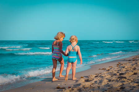 little girls walking on tropical beach, family at seaの写真素材