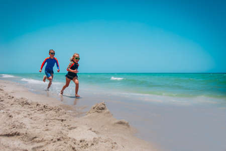 happy girl and boy run and play with water at beachの写真素材