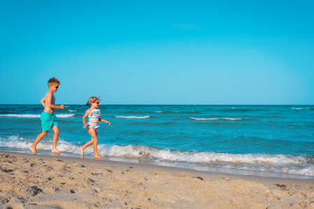 happy girl and boy run and play with water at beachの写真素材