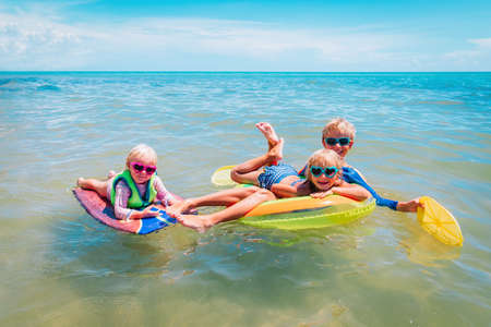happy kids, boy and girsl, swim on floatie at beachの写真素材
