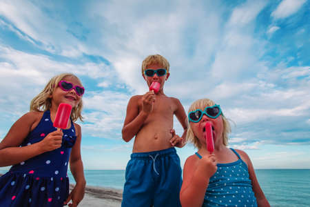 happy kids eating ice cream on beachの写真素材