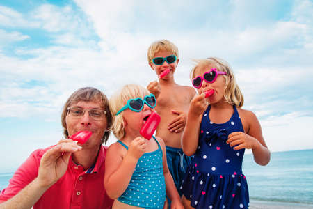 happy family- father and kids - eating ice cream on beachの写真素材