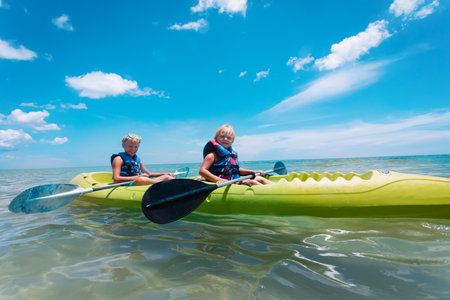 happy girl and boy kayaking on beach vacationの写真素材