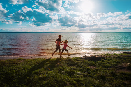 happy boy and girl run at sunset beach, kids have funの写真素材