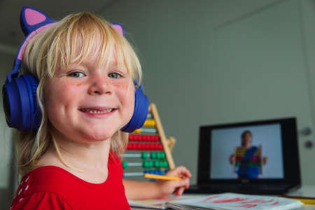 happy little girl learning at home, kid doing online lessonの写真素材