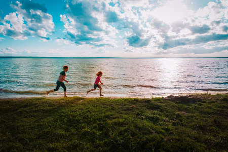 happy boy and girl run at sunset beach, kids have funの写真素材