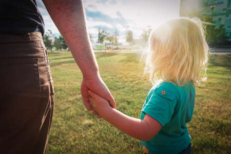 Father with a small daughter holding hands at sunsetの写真素材