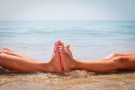 family feet on summer beach, kids play with waterの写真素材