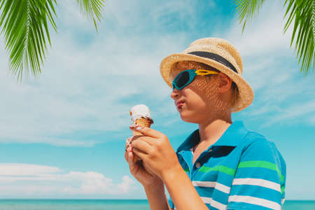 happy cute boy eating ice cream on beachの写真素材