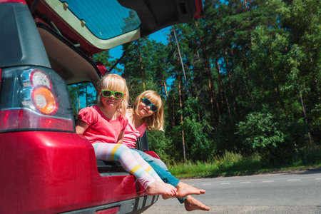 happy kids travel by car in nature, little girls on summer vacationの写真素材