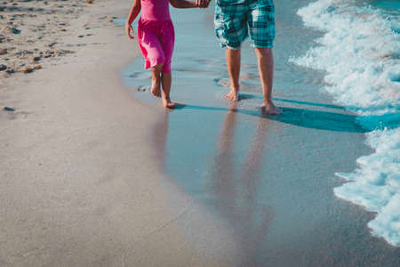 father and daughter walking on beach leaving footprint in sandの写真素材