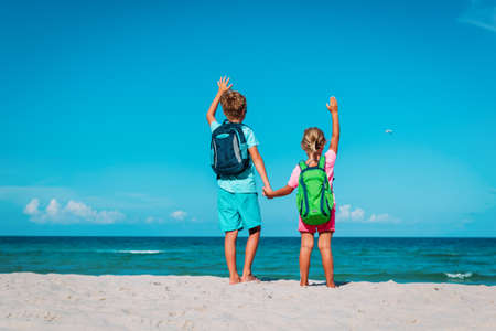 happy ravel on beach, boy and girls with backpack at seaの写真素材
