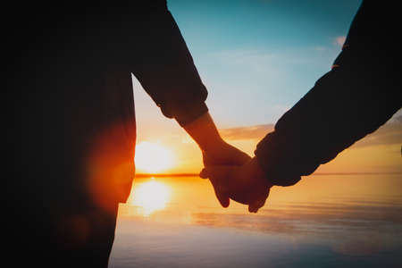 father and son holding hands at sunset natureの写真素材