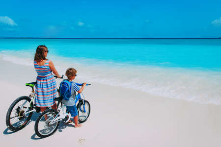 Happy mother and son biking at beachの写真素材