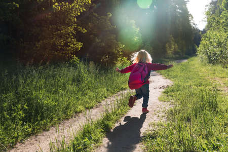 Silhouette of happy little girl running in sunset natureの写真素材