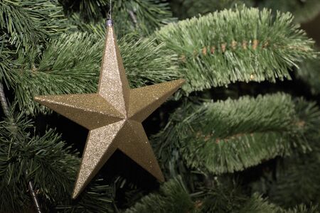 Christmas tree decorated with toys. Yellow star hanging on a branch of a Christmas tree.の写真素材