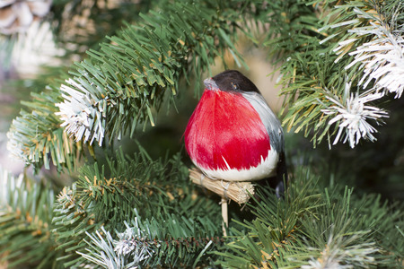 Bird a bullfinch sits on a branch of a tree. Christmas tree and a toy bird.の写真素材
