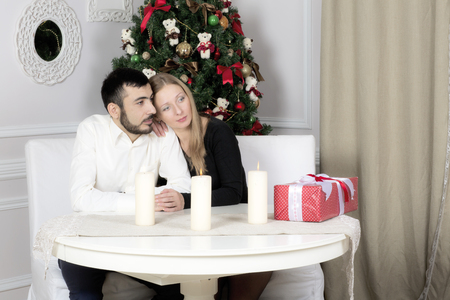 Portrait of a man and woman near the Christmas tree. Husband and wife looking thoughtfully to the side.の写真素材